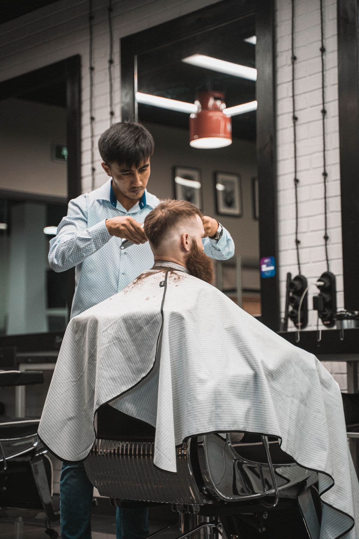 A barber giving a client a haircut, focused on the finishing details